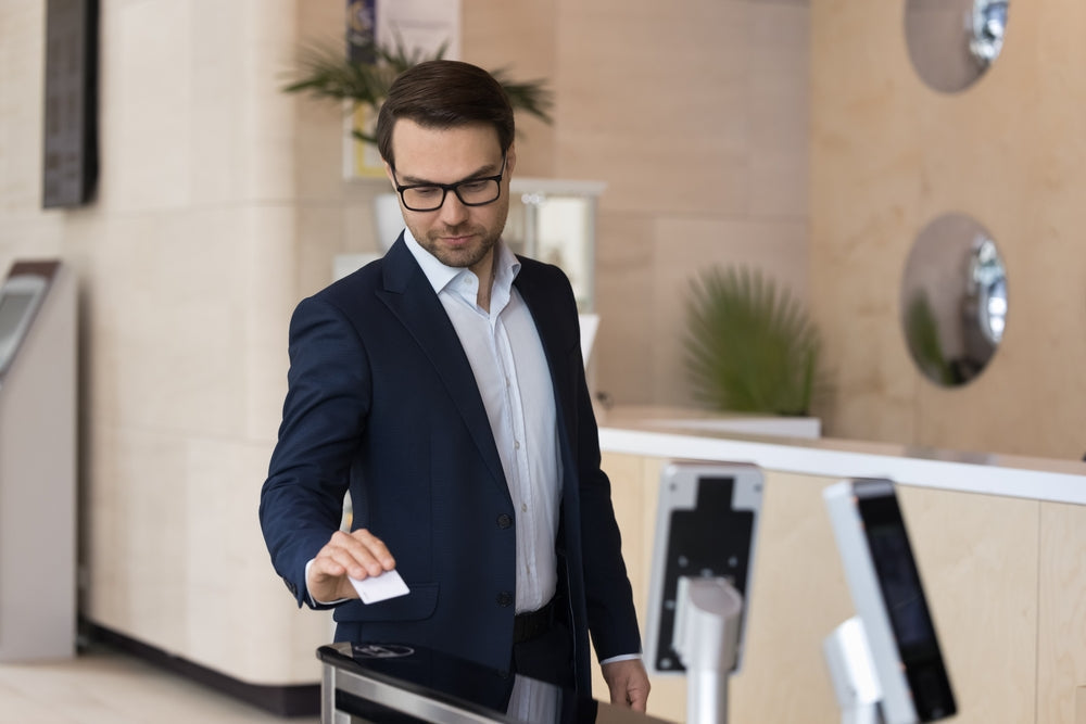 Corporate 1000 compatible proximity card being scanned on a wall-mounted reader at a secure office entrance.