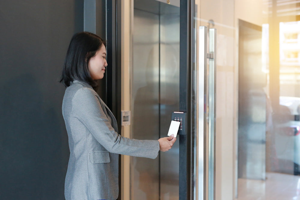 Woman scanning a company access card at an access control reader for secure entry.